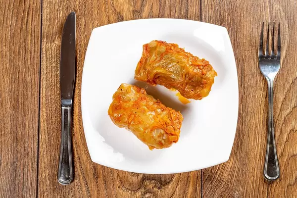 Stuffed stewed in tomato sauce with knife and fork on wooden brown background (Flip 2019)