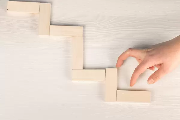 Success concept, hand climbing wooden block stairs on wooden background