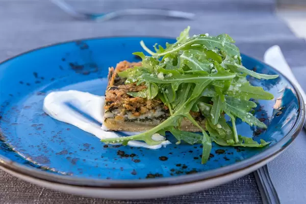 Summer quiche with rocket salad on a blue plate at Villa Vegana restaurant in Selva, Mallorca