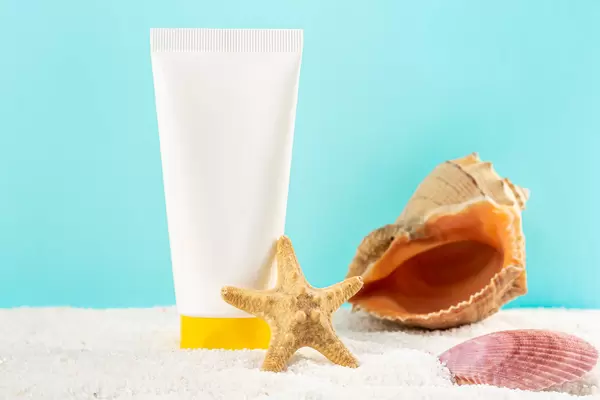 Summertime background, sunscreen cream with starfish, shells and small stones