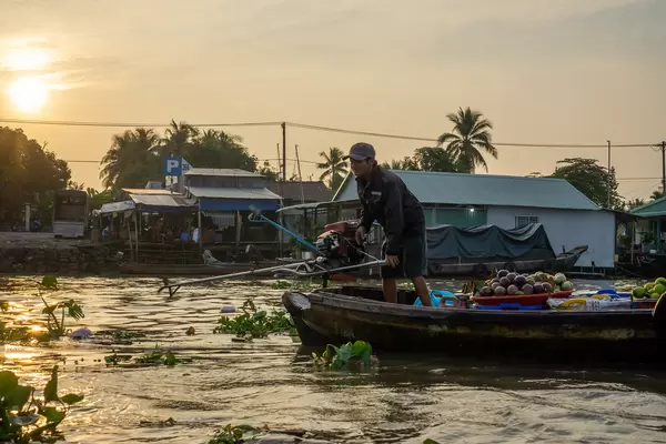 Sunrise at Cai Rang Floating Market with Vietnamese Man on a Wooden Boat selling Fresh Fruits in Can Tho, Vietnam
