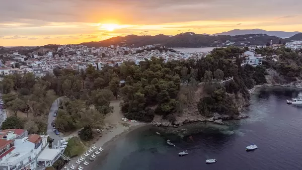 Sunset light over Greek island Skiathos: bird's eye view of the town and the coast with boats and trees