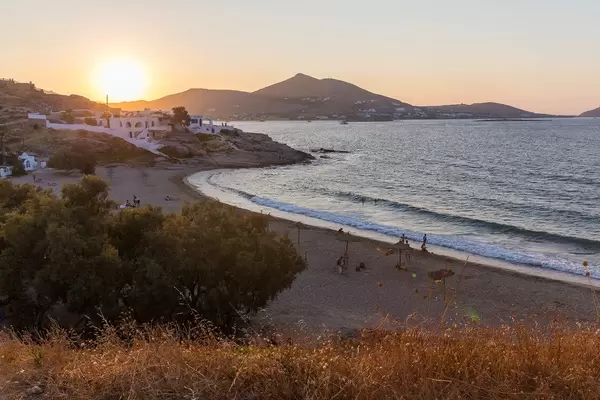 Sunset over Paros bathes beach and typical Greek buildings in golden light