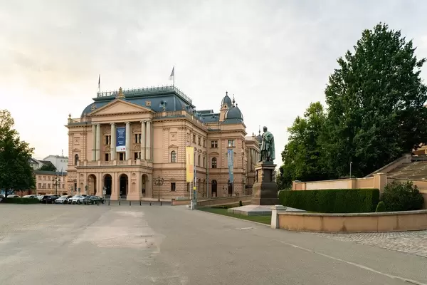 Sunset picture of German Mecklenburg State Theatre with statue of Paul Friedrich to its right