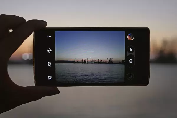 Sunset view through a smartphone taking a picture of it hold by a hand
