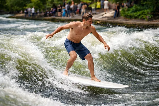 Surfer erklimmt die Eisbachwelle in München