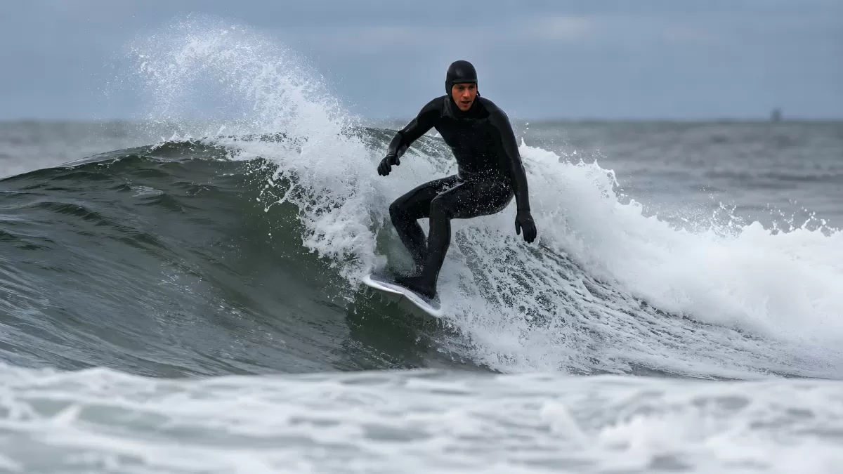 Surfer in schwarzem Neoprenanzug reitet steile Welle