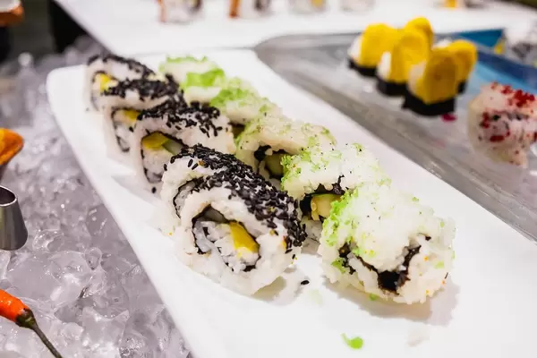Sushi mit Sesamtopping auf einem langen Tablett am gekühlten Büfettstand