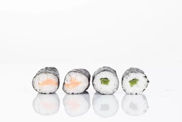 Sushi Rollen gefüllt mit grünem Paprika und Lachs im weißen HIntergrund