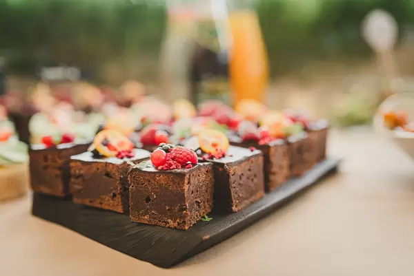 Süße Brownies in Quadrate geschnitten, mit bunten Beeren oben drauf