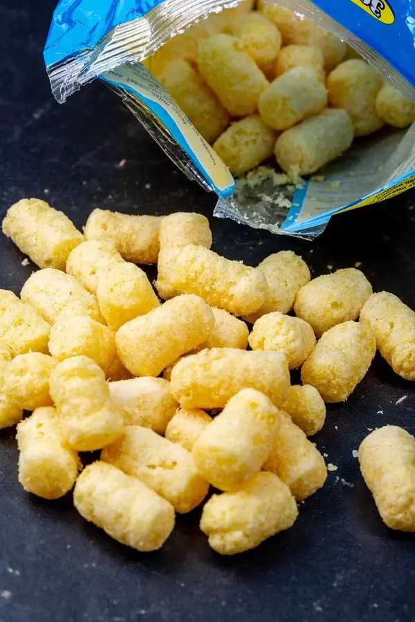 Süße Maisstäbchen fallen aus der Verpackung auf schwarzen Untergrund