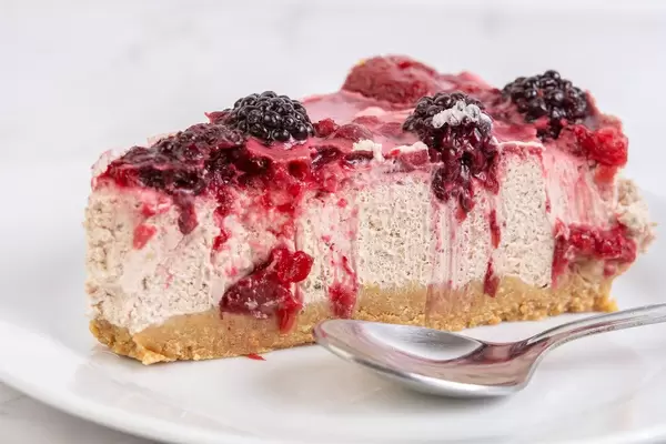 Süße Nachspeise: ein Stück Käsekuchen mit Brombeeren und Löffel