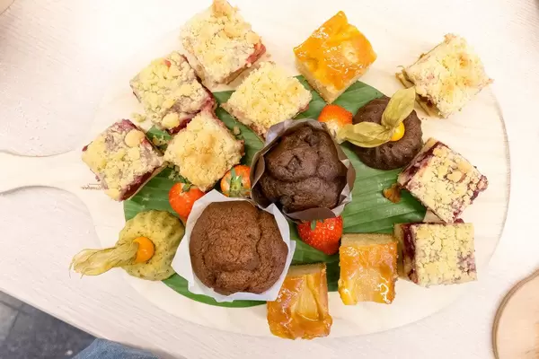 Süßer Nachtisch mit Früchtekuchen und Schokomuffins auf einem Holzbrett aus der Sicht von oben, beim Barcamp OMWest19 von AXA in Köln