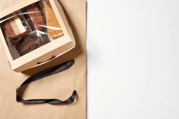 Süßes Geschenk: vier Stück Torte in Verpackung aus Pappe und Plastik mit Platz für Text rechts