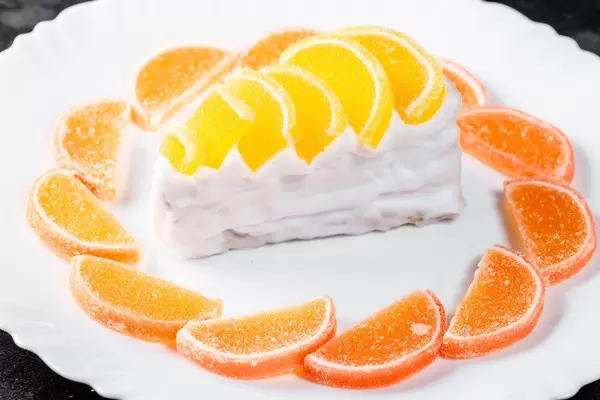 Sweet dessert with cream, orange and lemon marmalade on a white plate