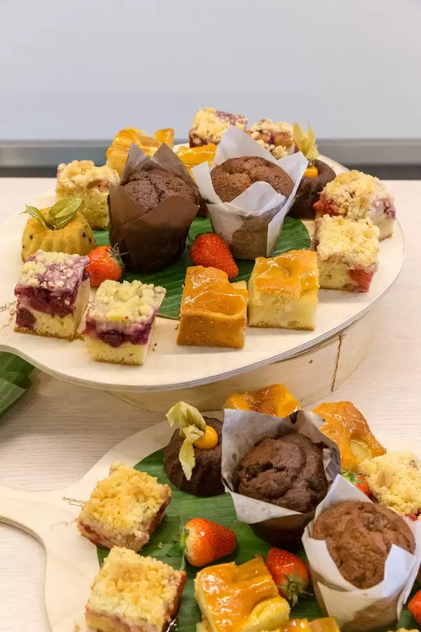 Sweet desserts served on round wooden boards with cakes, fruits and muffins at lunch in the AXA house during the Barcamp OMWest19 in Cologne, Germany