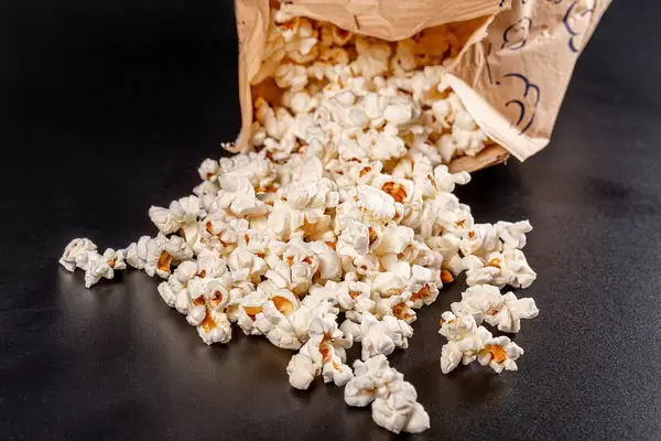 Sweet fresh popcorn poured out on black background