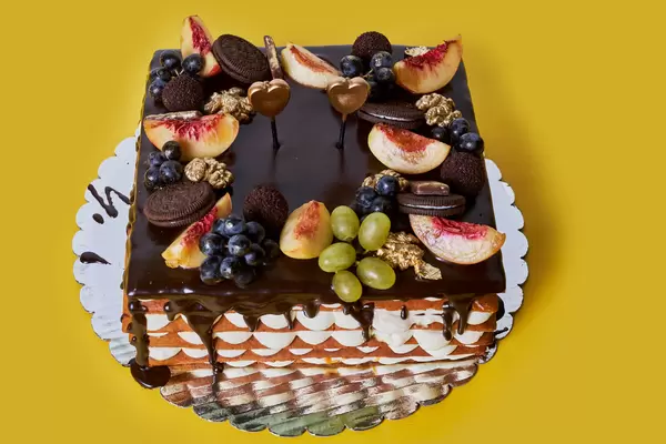 Sweet homemade chocolate cake with biscuit, grapes and peaches