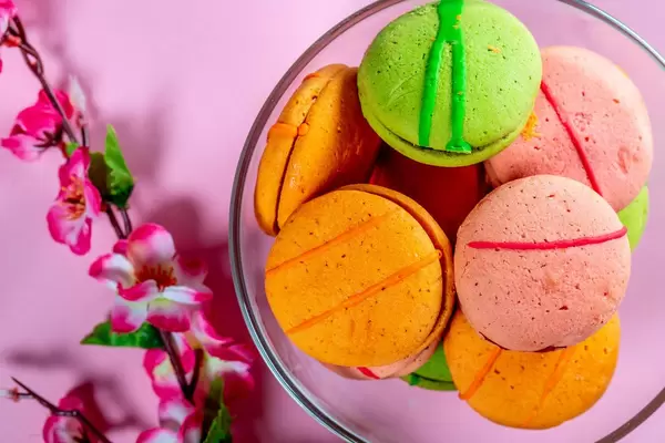 Sweet multicolored macarons on pink background.