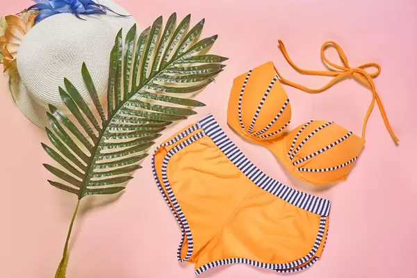 Swimsuit and beach items on pink