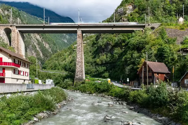 Swiss train speeding on an old tall brick bridge