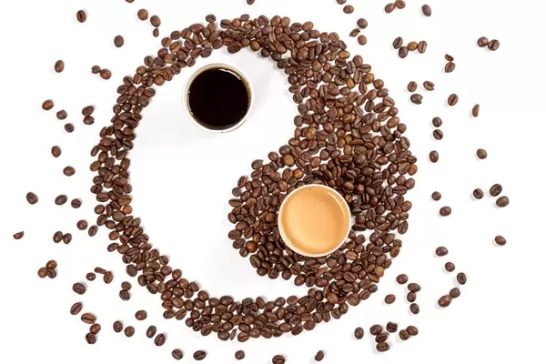 Symbol yin yang from roasted coffee and coffee in paper cups, top view