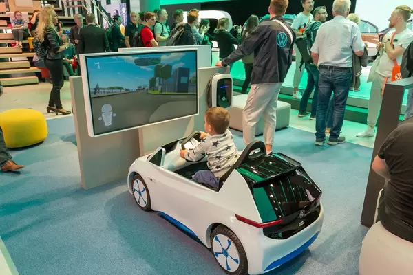 Symbolbild für umweltfreundliche, zukunftsorientierte Autos: kleines Kind spielt ein Fahrsimulationsspiel im Modellauto von VW