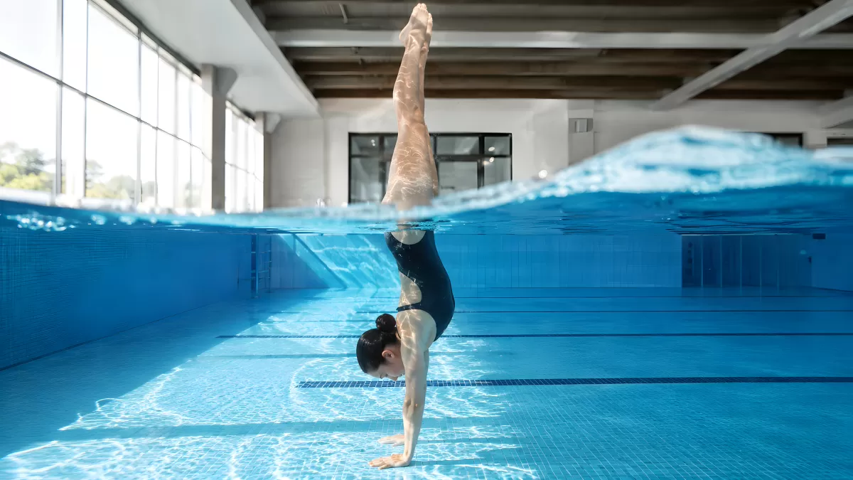 Synchronschwimmerin macht Handstand im Hallenbad