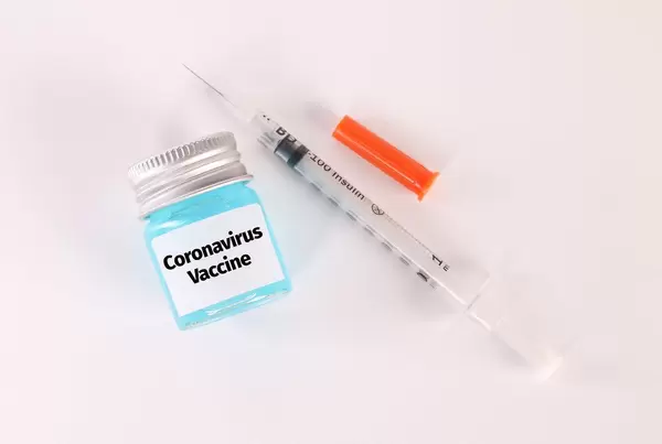 Syringe and bottle with blue fluid and Coronavirus Vaccine text on white background