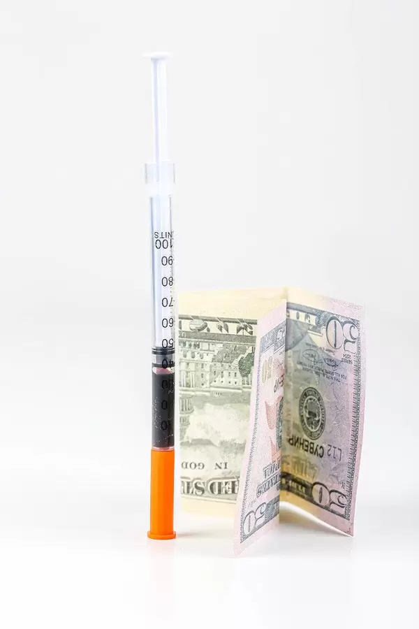 Syringe and dollar bill on white background