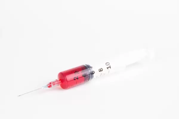 Syringe with blood on white background