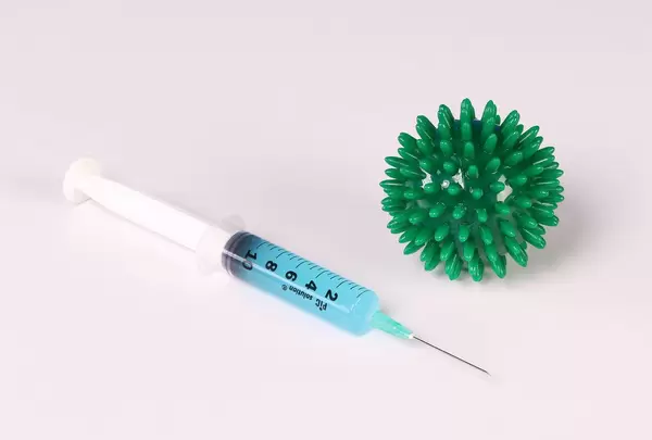 Syringe with blue fluid and Coronavirs bacteria on white background