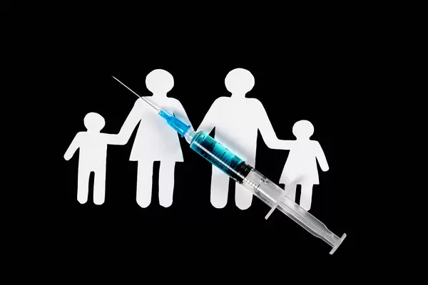 Syringe with family cutout from paper on black background