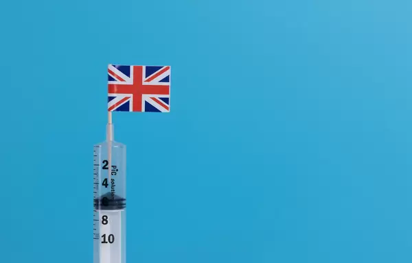 Syringe with flag of UK on blue background