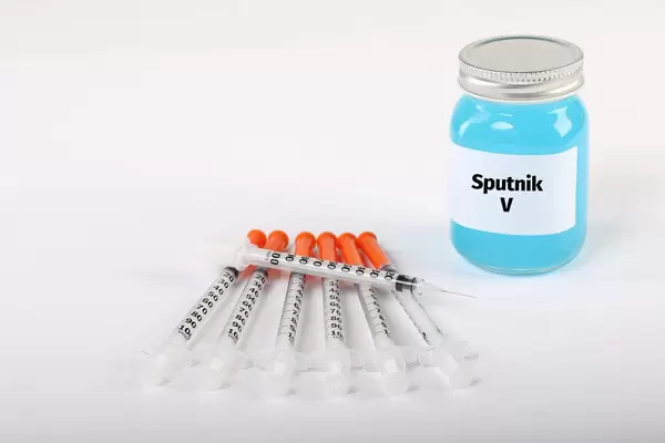 Syringes with bottle with Sputnik V vaccine on white background