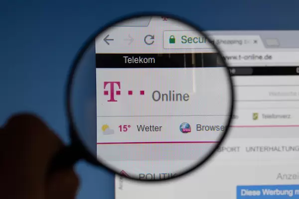 T-Online-Logo am PC-Monitor, durch eine Lupe fotografiert
