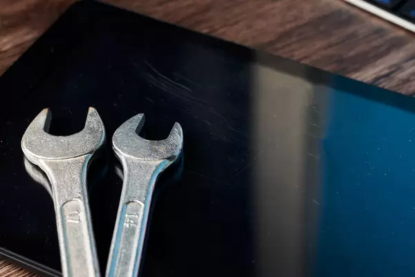 Tablet computer and wrench on wood background