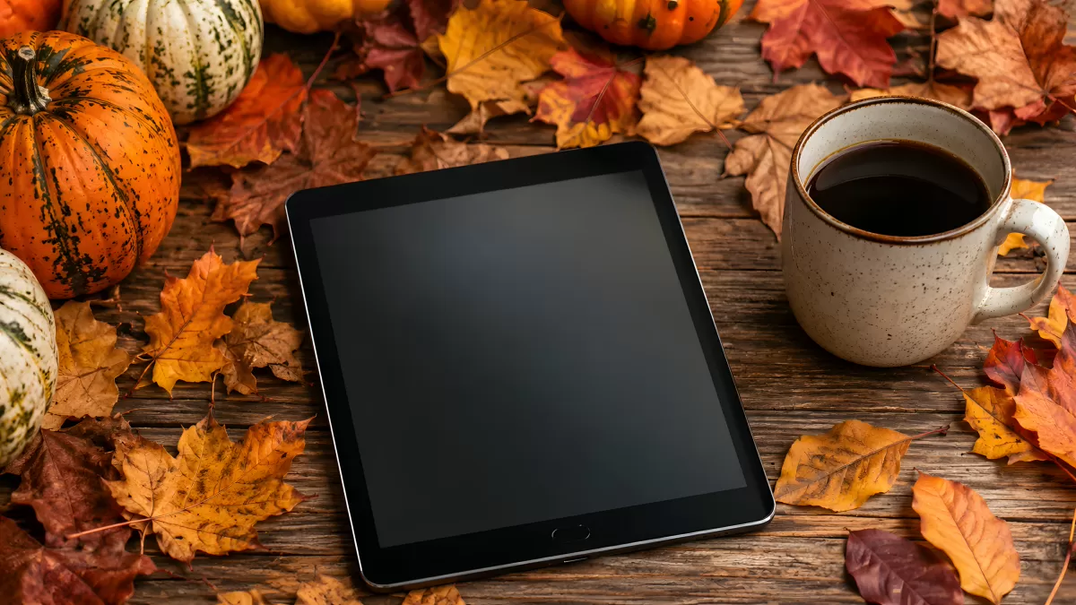 Tablet und Kaffee mit Herbstdeko auf Holztisch