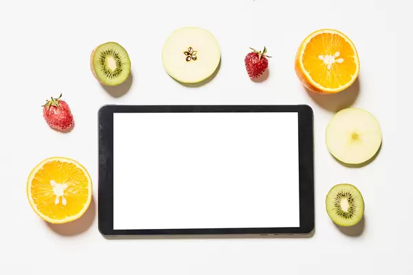 Tablet with empty white screen and various fruits slices around it