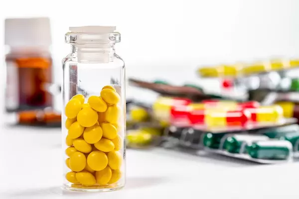 Tablets in a glass bottle and blisters on a white background (Flip 2019)