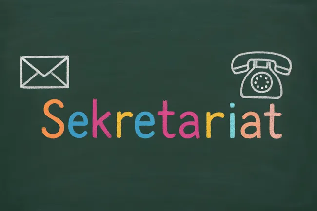 Tafel mit buntem Sekretariatslogo und Büroutensilien