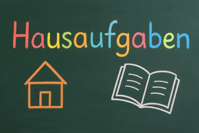 Tafel mit Hausaufgabensymbol und offenes Buch