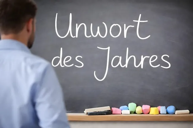 Tafel mit Kreide-Aufschrift 'Unwort des Jahres' im Klassenzimmer