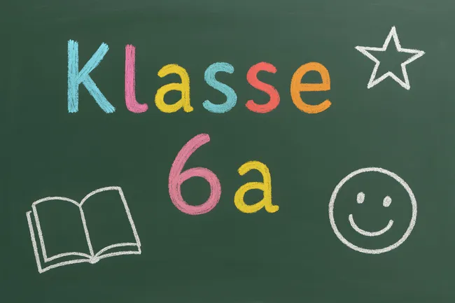 Tafel mit Schulklasse-Aufschrift und fröhlichen Symbolen