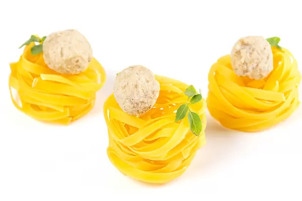 Tagliatelle with raw meatballs placed on a white background
