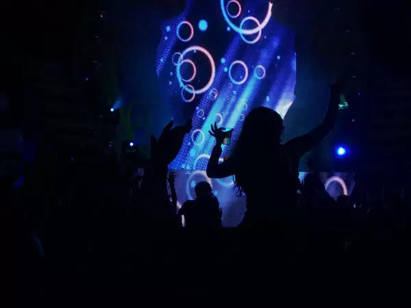 Tanzende Besucher mit der Light-Show im Hintergrund - Musikfestival Tomorrowland 2014