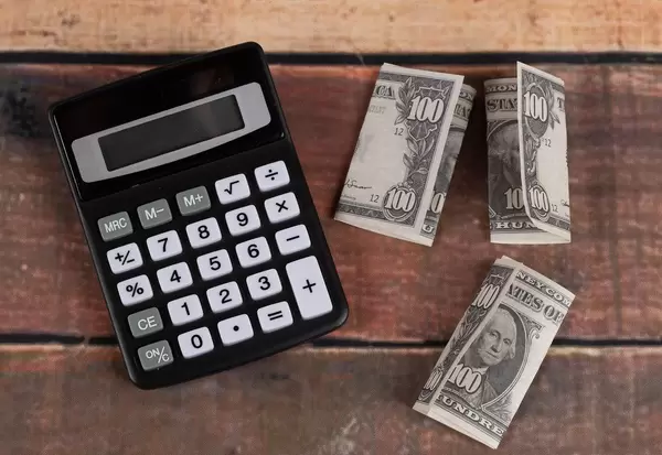 Taschenrechner mit amerikanischem Geld auf einem Holztisch