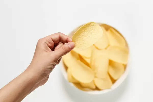 Tasting salty chips from a bowl