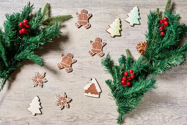 Tasty Christmas cookies and decorative pine tree branches on wood