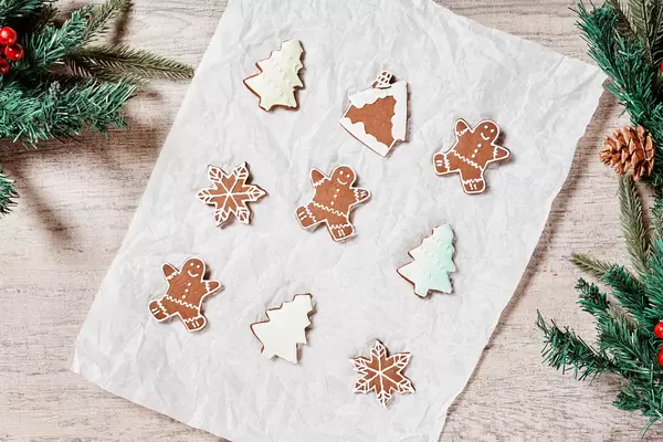 Tasty Christmas cookies and decorative pine tree branches on wooden background